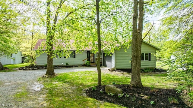 view of front facade with dirt driveway, a front lawn, and an attached garage