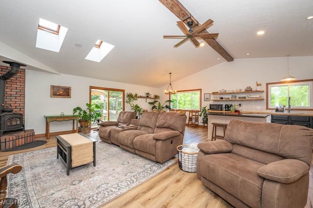 living room featuring light wood-type flooring, a wood stove, plenty of natural light, a chandelier, and recessed lighting