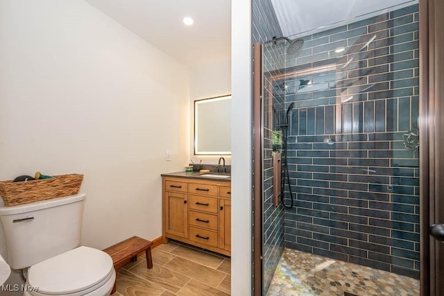 full bathroom with a tile shower, vanity, toilet, and recessed lighting
