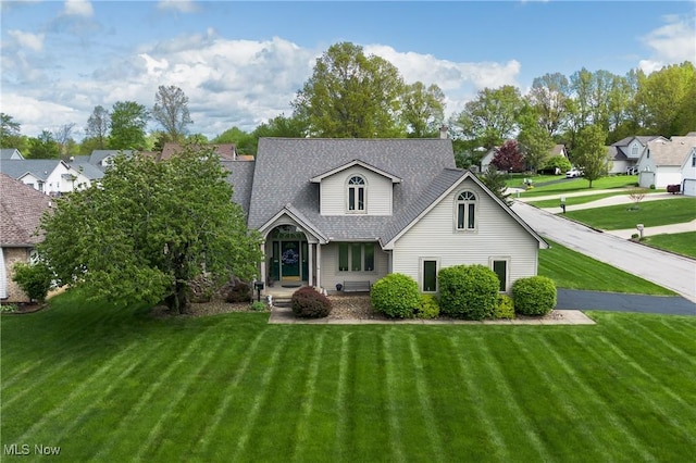 traditional home featuring a front lawn and roof with shingles