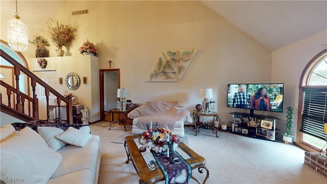 carpeted living room featuring high vaulted ceiling and stairs
