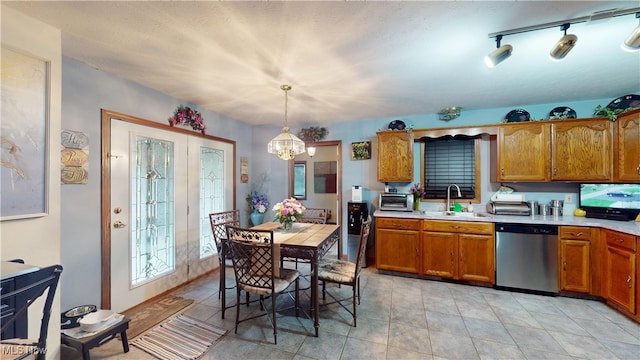 kitchen featuring stainless steel dishwasher, a sink, a chandelier, and brown cabinets