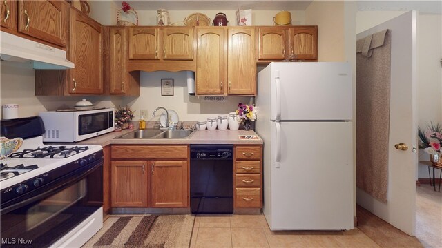 kitchen featuring white appliances, a sink, under cabinet range hood, light countertops, and brown cabinets