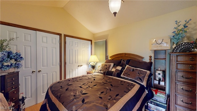 bedroom featuring vaulted ceiling and multiple closets