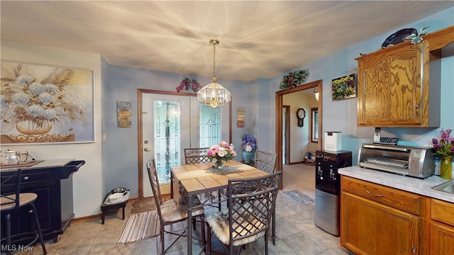 dining room featuring a chandelier, light tile patterned floors, and baseboards