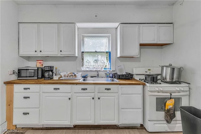 1348 Himrod Ave, Youngstown, OH 44506 - kitchen with white range with gas cooktop, a sink, butcher block countertops, stainless steel microwave, and white cabinetry