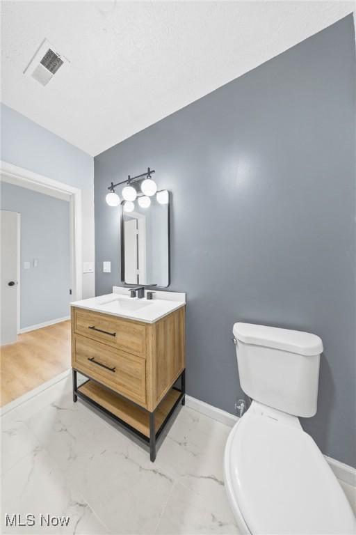 9324 Columbia Rd, Olmsted Falls, OH 44138 - bathroom featuring marble look tiles, baseboards, toilet, and vanity