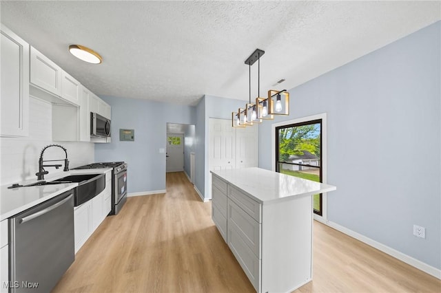 9324 Columbia Rd, Olmsted Falls, OH 44138 - kitchen featuring stainless steel appliances, light wood finished floors, a kitchen island, a textured ceiling, and light countertops