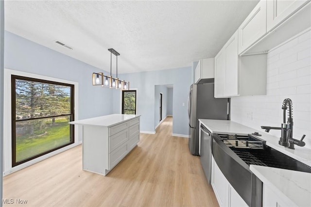 9324 Columbia Rd, Olmsted Falls, OH 44138 - kitchen featuring light wood-type flooring, a sink, a textured ceiling, white cabinets, and a kitchen island