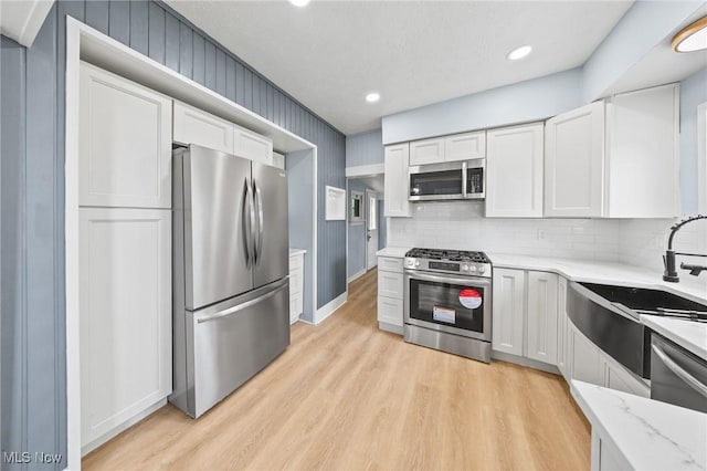9324 Columbia Rd, Olmsted Falls, OH 44138 - kitchen featuring stainless steel appliances, white cabinets, light wood finished floors, tasteful backsplash, and a sink