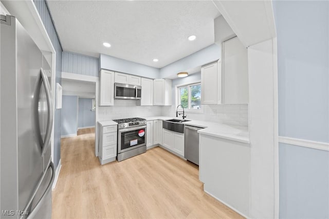 9324 Columbia Rd, Olmsted Falls, OH 44138 - kitchen with stainless steel appliances, a sink, backsplash, light wood-type flooring, and a textured ceiling