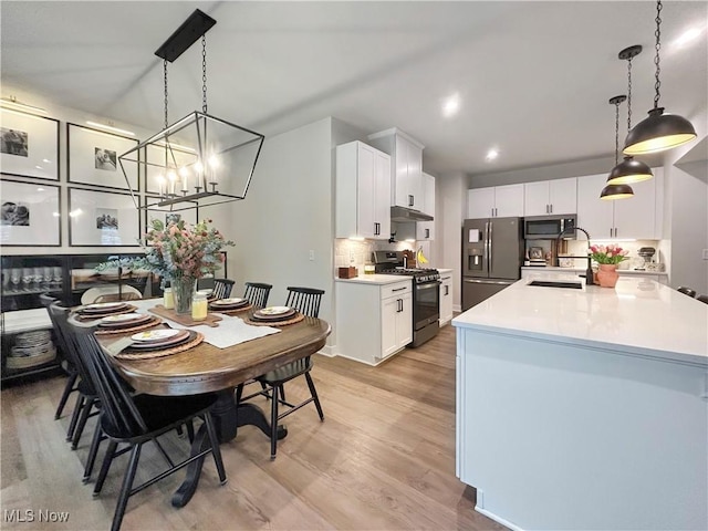 1810 Muirfield Ln, Painesville, OH 44077 - kitchen with appliances with stainless steel finishes, a sink, a chandelier, decorative backsplash, and light wood-style floors