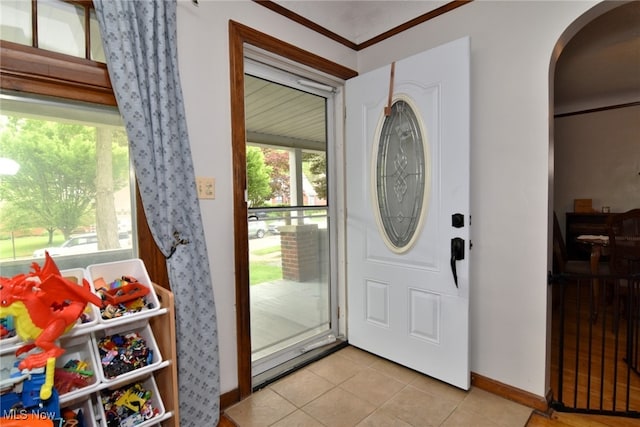foyer with arched walkways, light tile patterned floors, baseboards, and plenty of natural light