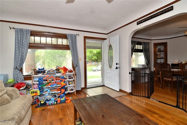 entryway featuring arched walkways, wood finished floors, ornamental molding, and baseboards