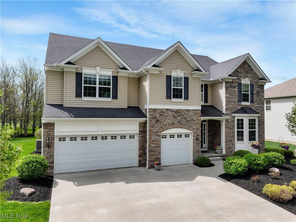 1486 Park Ridge Ave, Twinsburg, OH 44087 - view of front of property featuring stone siding, a garage, concrete driveway, and roof with shingles