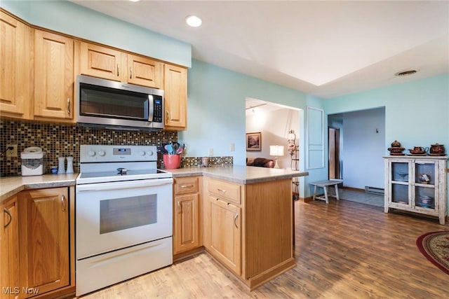kitchen featuring stainless steel microwave, white range with electric stovetop, a peninsula, light brown cabinetry, and decorative backsplash