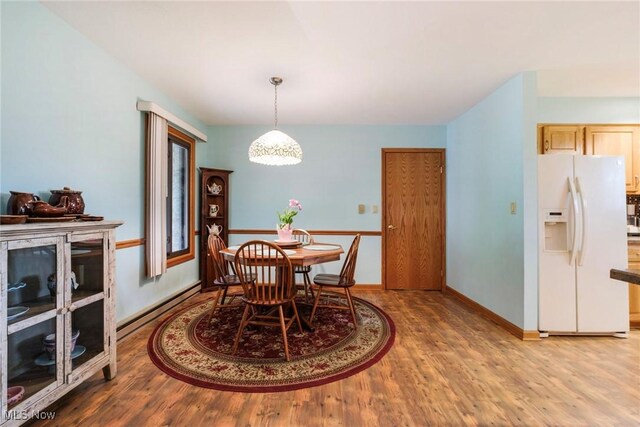 dining space featuring baseboard heating, wood finished floors, and baseboards