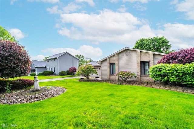view of grassy yard featuring concrete driveway and a garage