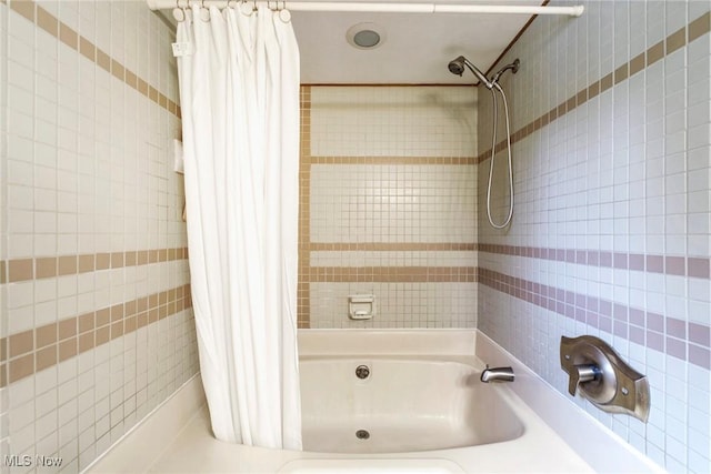 bathroom with shower / bathtub combination with curtain and tile walls