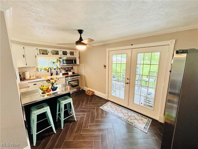 211 Kenwood St, Marietta, OH 45750 - kitchen with appliances with stainless steel finishes, french doors, a textured ceiling, white cabinetry, and backsplash