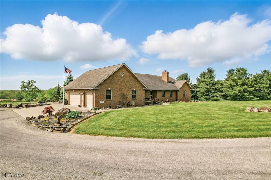 12094 Snode St NE, Alliance, OH 44601 - view of front of house with a chimney, concrete driveway, stone siding, and a front yard