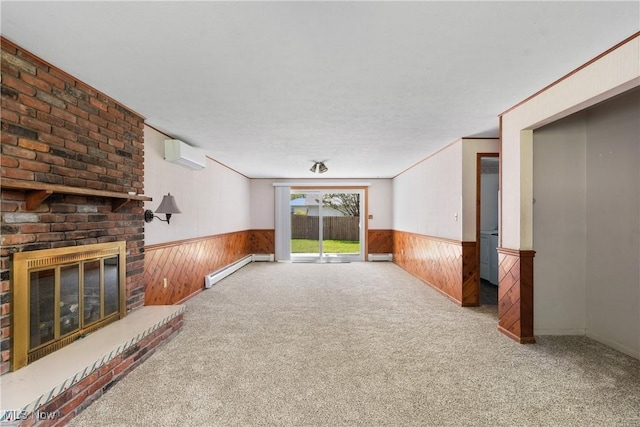 unfurnished living room featuring wainscoting, wood walls, carpet, a brick fireplace, and a baseboard radiator