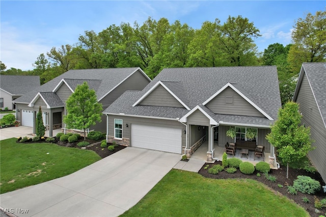 craftsman house featuring a shingled roof, a garage, stone siding, a front yard, and concrete driveway