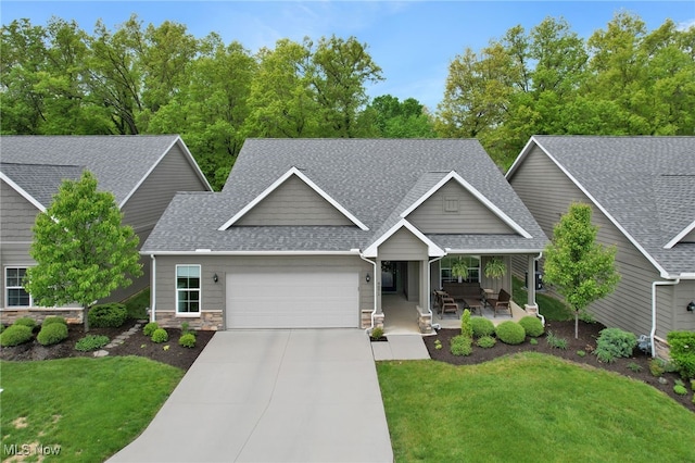 craftsman inspired home with roof with shingles, a garage, covered porch, driveway, and a front lawn