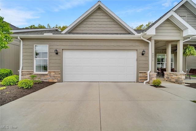 view of front facade featuring stone siding, driveway, a garage, and a shingled roof