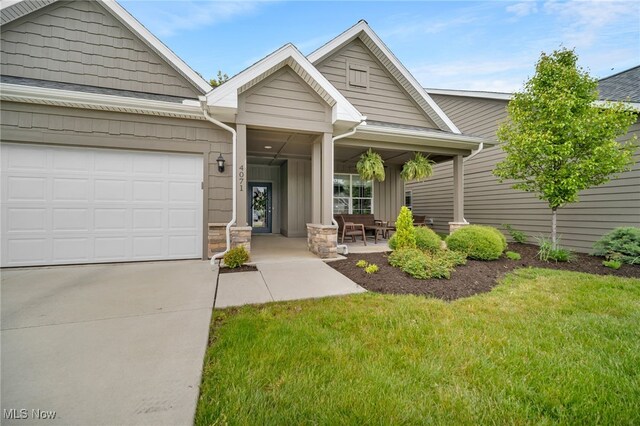 view of front of home featuring driveway, a porch, an attached garage, and a front lawn