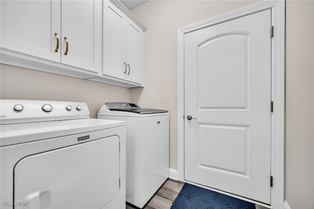 clothes washing area with washing machine and clothes dryer, cabinet space, light wood-type flooring, and baseboards