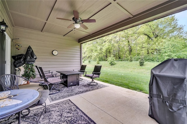 view of patio with grilling area, ceiling fan, a fire pit, and a wooded view