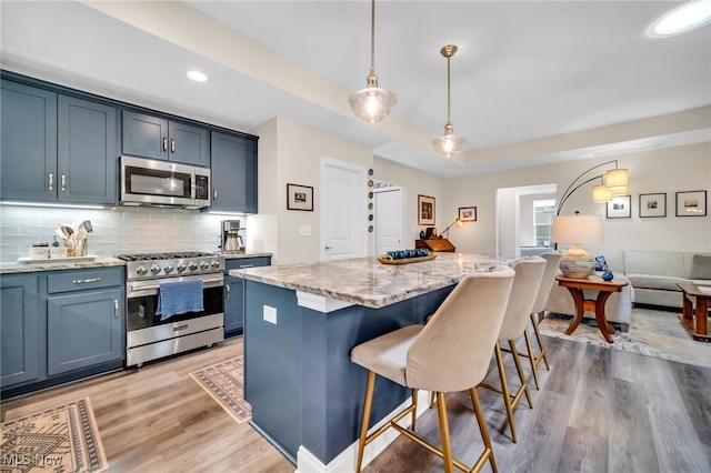 kitchen featuring stainless steel appliances, light stone countertops, light wood finished floors, a kitchen bar, and recessed lighting