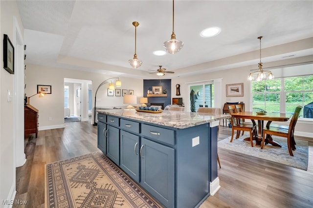 kitchen featuring ceiling fan, dark wood-style flooring, a raised ceiling, and plenty of natural light