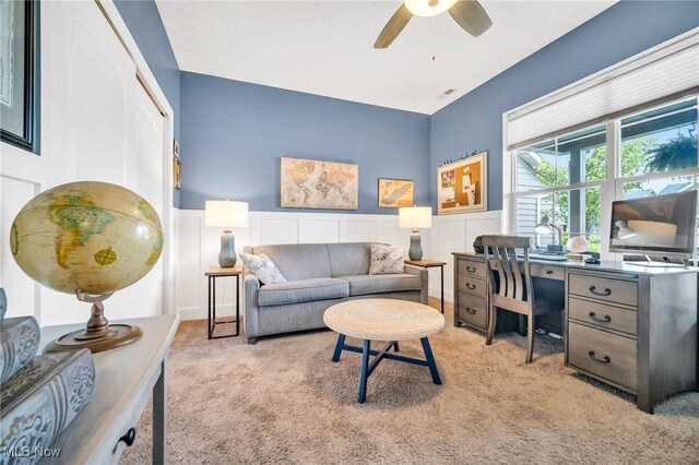 home office with carpet flooring, ceiling fan, wainscoting, and a decorative wall