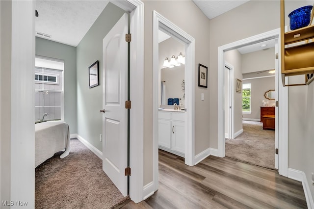 corridor featuring carpet flooring, baseboards, and wood finished floors