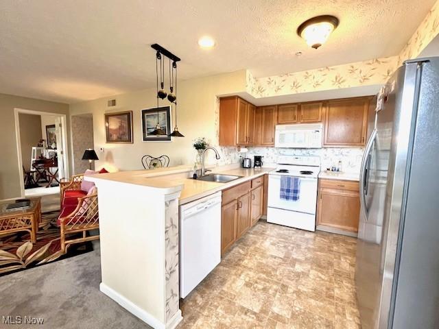 23003 Chandlers Ln Unit 219, Olmsted Falls, OH 44138 - kitchen featuring white appliances, a sink, brown cabinetry, a peninsula, and light countertops