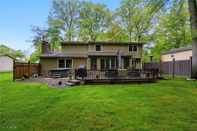 back of house with a hot tub, a wooden deck, and a chimney