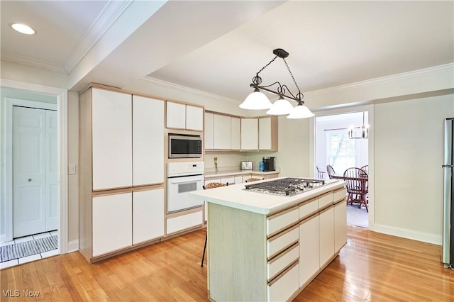 7304 Glastonbury Dr, Hudson, OH 44236 - kitchen featuring appliances with stainless steel finishes, light wood-type flooring, light countertops, a kitchen island, and white cabinetry
