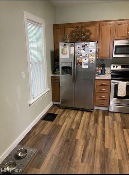 566 N Walnut St, Wooster, OH 44691 - kitchen featuring appliances with stainless steel finishes, brown cabinetry, light countertops, dark wood-style flooring, and baseboards