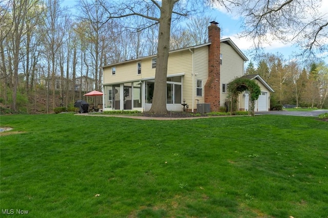 6352 Creekside Trl, Solon, OH 44139 - rear view of property featuring a chimney, central AC unit, a sunroom, driveway, and a yard