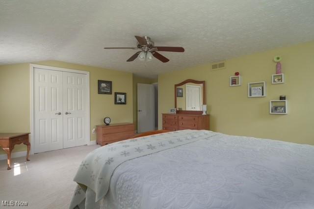 6352 Creekside Trl, Solon, OH 44139 - carpeted bedroom with a closet, a textured ceiling, a ceiling fan, and vaulted ceiling