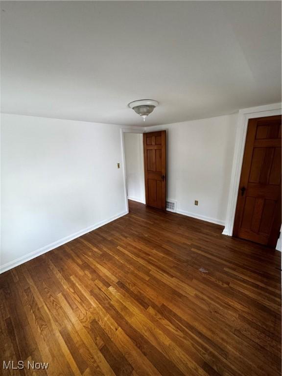 unfurnished room with dark wood finished floors and baseboards