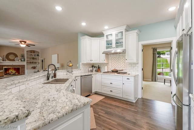 kitchen featuring appliances with stainless steel finishes, a sink, ceiling fan, white cabinetry, and light stone counters