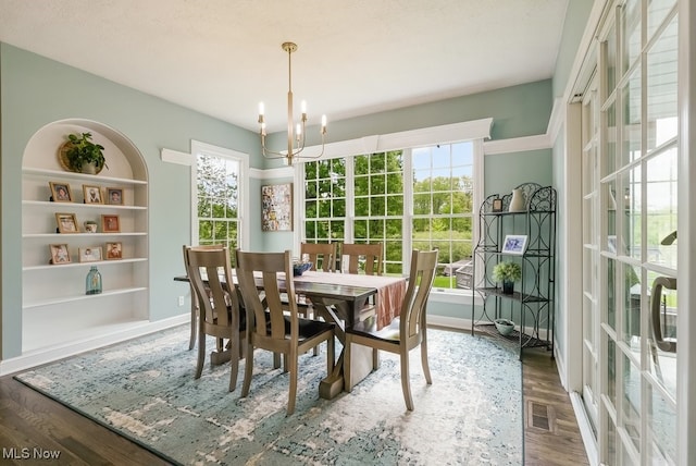 dining space with a chandelier, plenty of natural light, wood finished floors, and baseboards