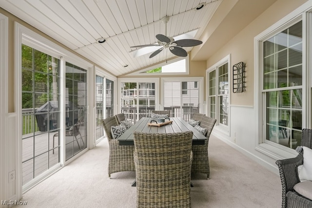 sunroom with carpet flooring, a skylight, wainscoting, and lofted ceiling