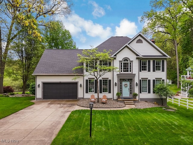 colonial house featuring concrete driveway, an attached garage, and roof with shingles