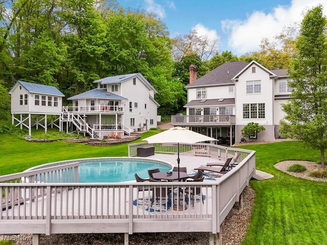 outdoor pool featuring a wooden deck and a lawn