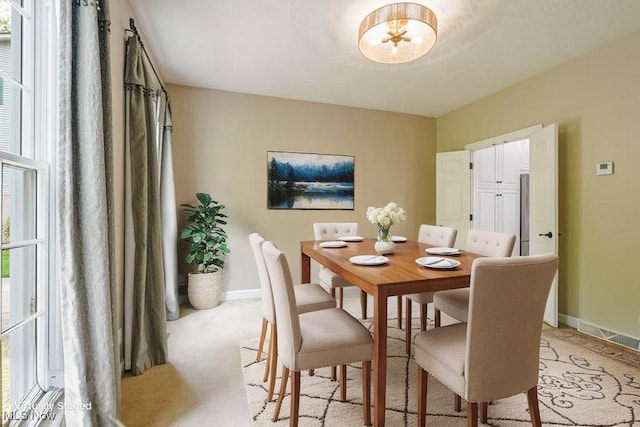 dining space with baseboards, light colored carpet, and a chandelier