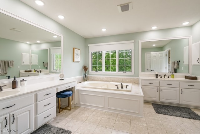 bathroom with tile patterned floors, recessed lighting, a bath, and two vanities